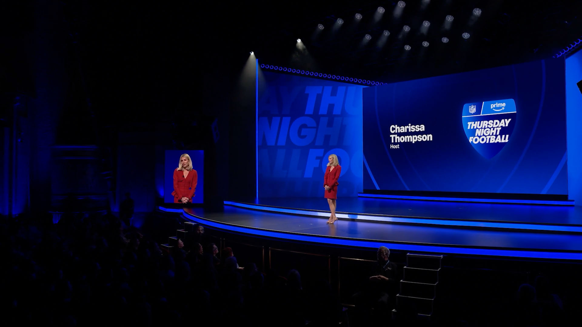 Charissa Thompson on a blue-lit stage with her name and the Prime Thursday Night Football logo.